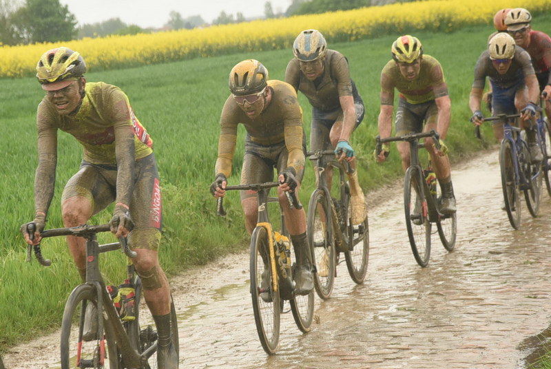 Michiel Lambrecht and I alongside 3 other riders on the first few pavés of 22. The cobbles covered in a greasy slime